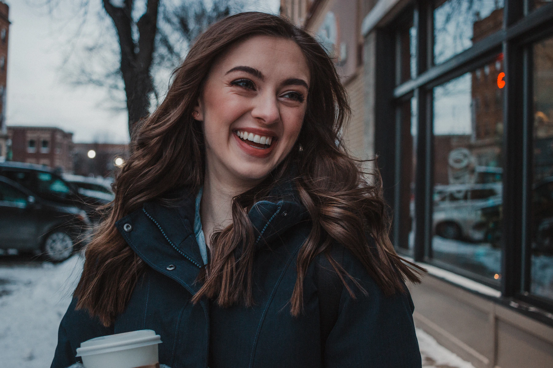 Smiling woman holding a coffee outside a cafe